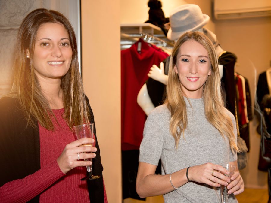 two women having drink infront of a retail store